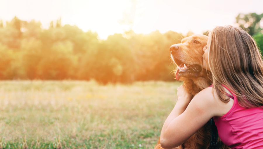 Kobieta siedziała z psem na zewnątrz w polu, całując jego pysk